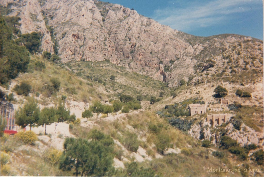 Las casas pegadas a la ermita a la derecha y parking a la izquierda